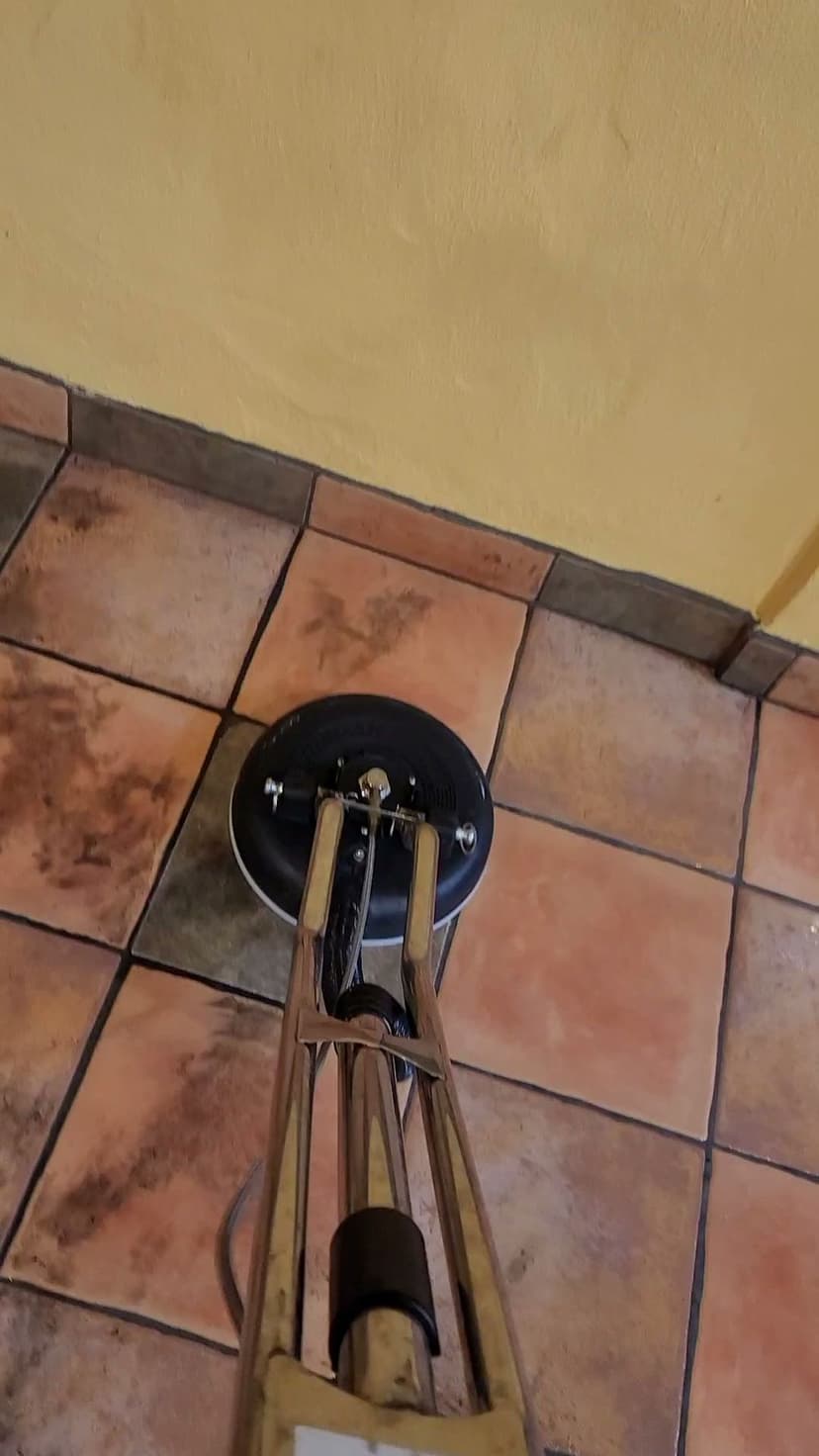 Floor cleaning machine on tiled floor with yellow wall in background.